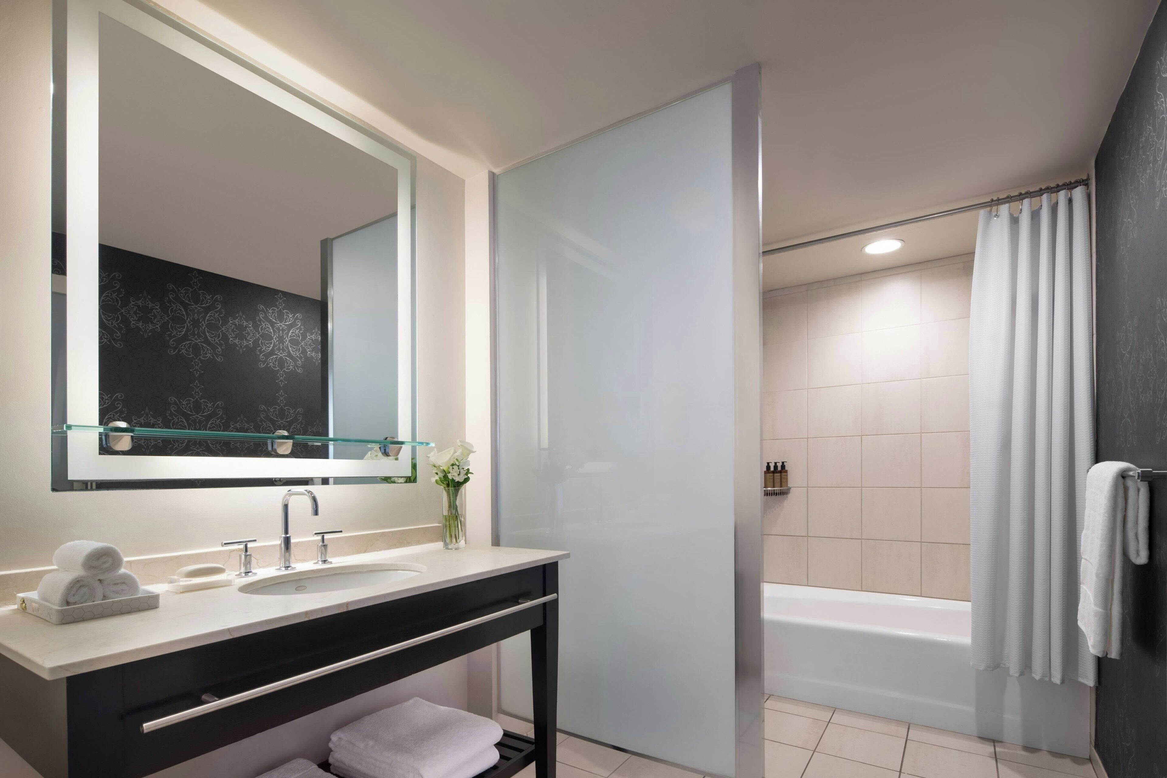 Un baño moderno con cabina de ducha de vidrio, bañera y tocador con espejo y lavabo.