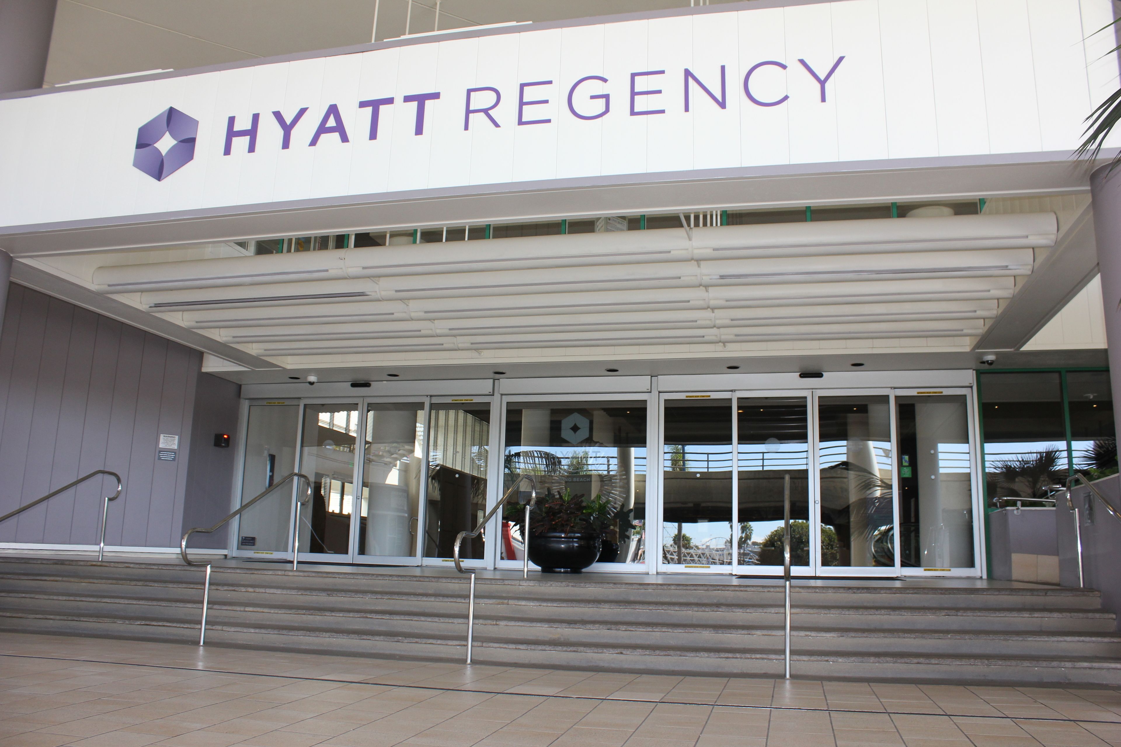 The exterior of the Hyatt Regency hotel with a modern design, featuring a prominent entrance with glass doors and a staircase leading up to the entrance.