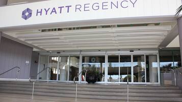 The exterior of the Hyatt Regency hotel with a modern design, featuring a prominent entrance with glass doors and a staircase leading up to the entrance.