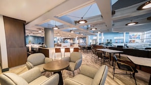 A spacious indoor area with multiple seating arrangements, including round tables and chairs, and a central column. - Hyatt Regency Long Beach (Long Beach)