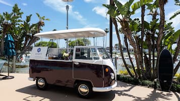 A vintage van with a canopy, branded with "HYATT REGENCY," parked near palm trees and a street lamp.