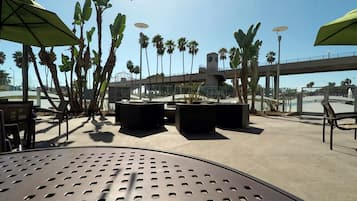 Un espace extérieur aménagé avec des tables et des chaises, entouré de palmiers et offrant une vue sur un ciel dégagé.