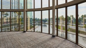 A spacious room with large windows, a patterned carpet, and a view of a river and buildings. - Hyatt Regency Long Beach (Long Beach)