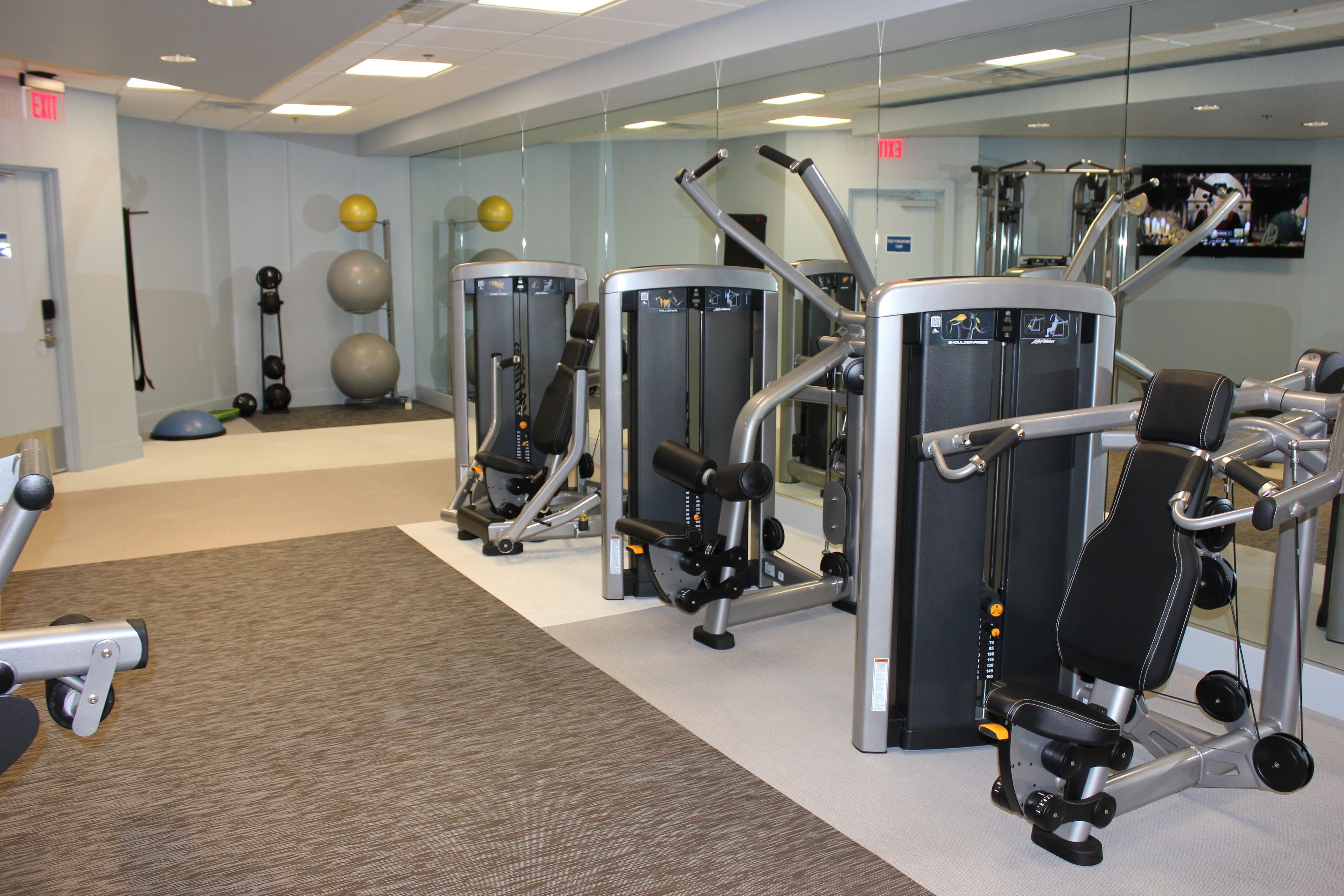 A gym with exercise machines, a mirror, and exercise balls.