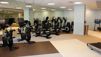 A gym with various exercise machines, including treadmills and stationary bikes, arranged in rows.