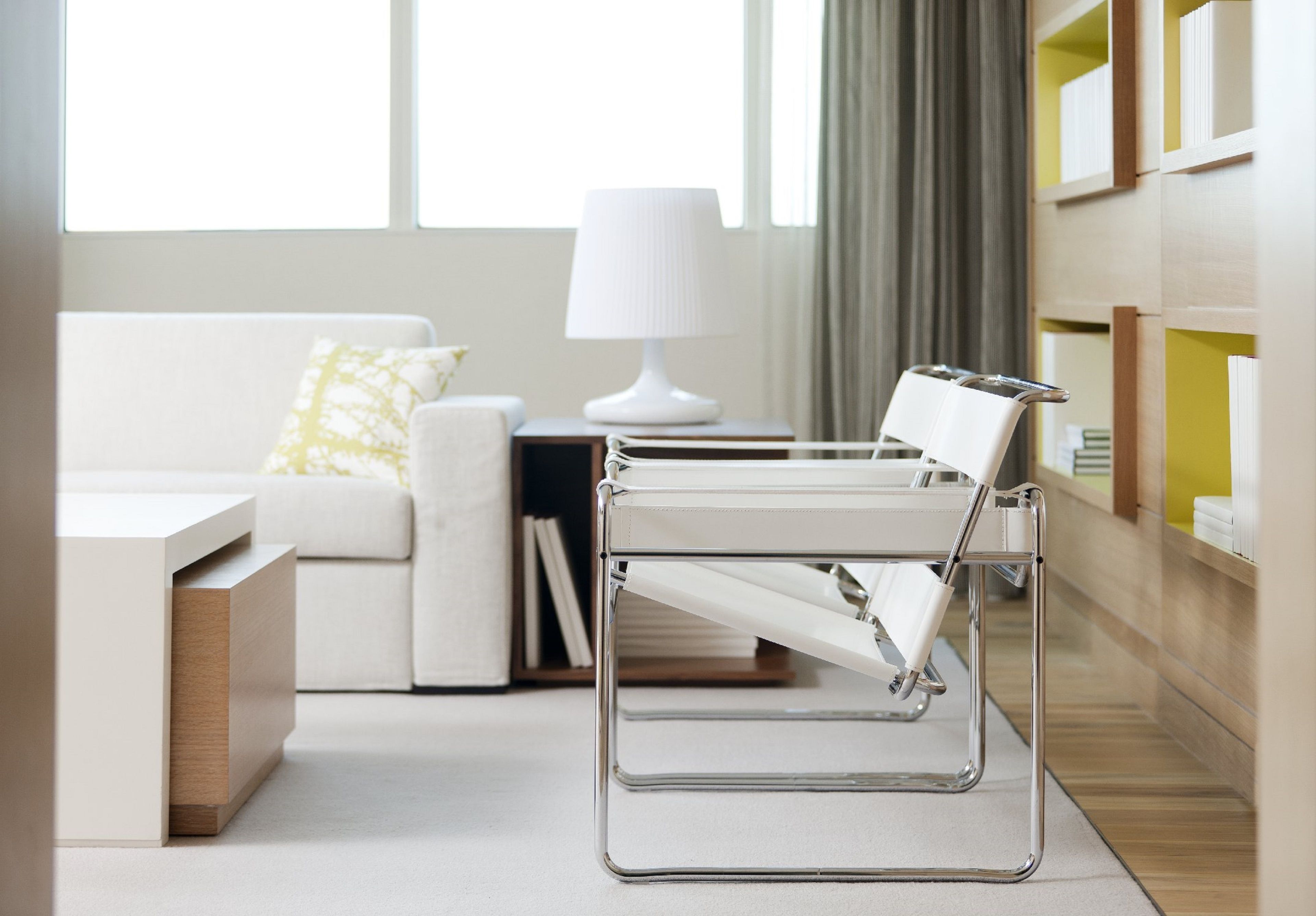 A modern living room with a white sofa, a side table with a lamp, and a bookshelf.