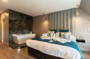 Una habitación de hotel moderna con una cama grande, una bañera y un tocador con espejo.