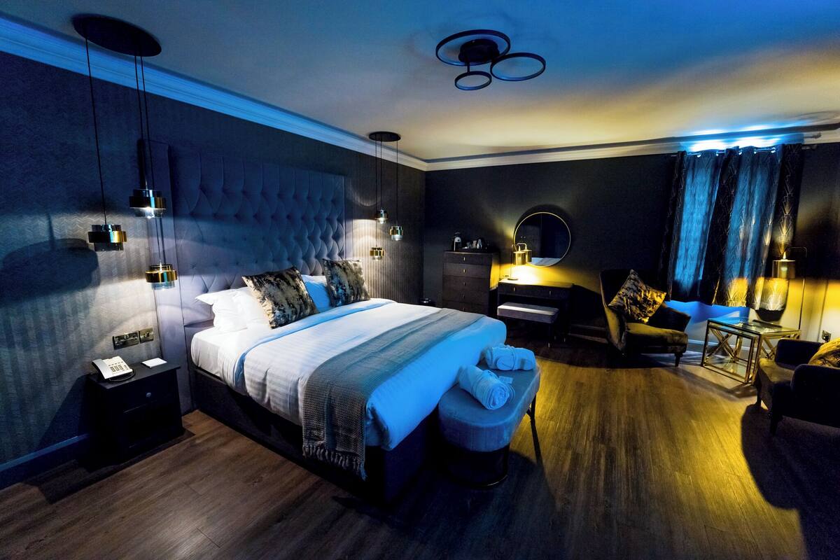 Une chambre d’hôtel moderne, dotée d’un grand lit, de tables de chevet, d’un bureau et d’une chaise.