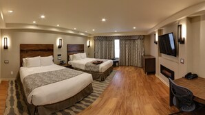 Een hotelkamer met twee bedden, een bureau, een stoel, een televisie en een open haard.