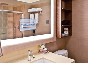 A hotel bathroom with a sink, mirror, towel rack, and a sign that reads "HOTEL STRATA".