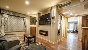 Een moderne woonkamer met een open haard, comfortabele zithoek en een grote flatscreen televisie.
