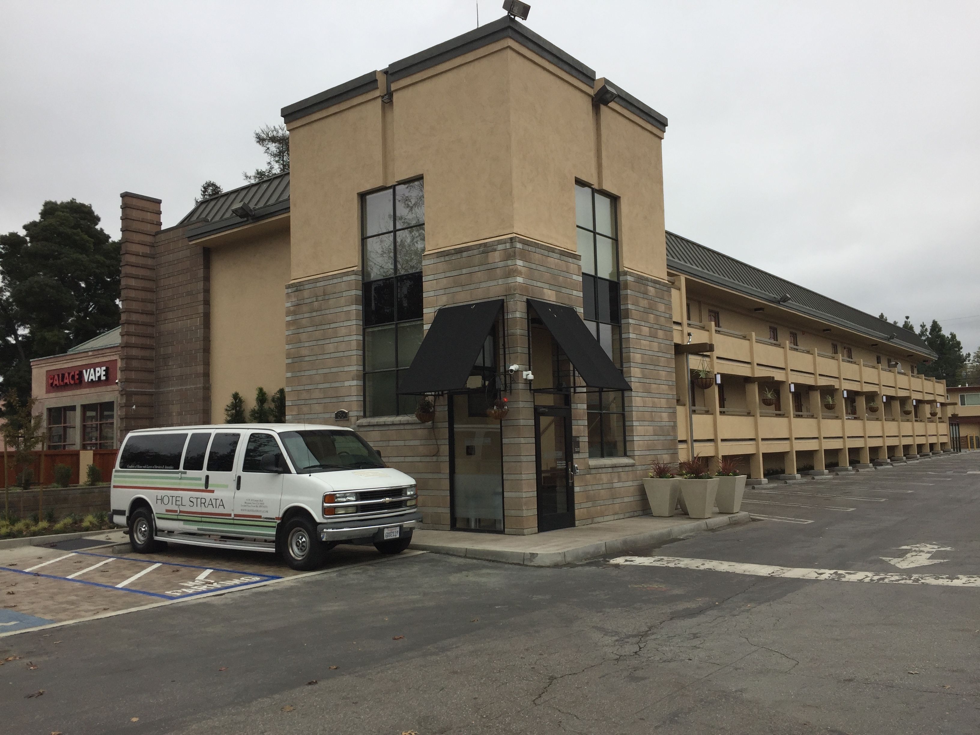 A building with a parking lot and a white van parked in front.