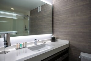 A modern bathroom with a large mirror, a white sink, and a glass shower enclosure.