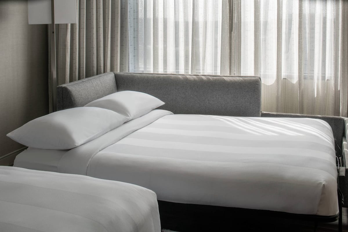 A hotel room with a large bed, a smaller bed, and a headboard.