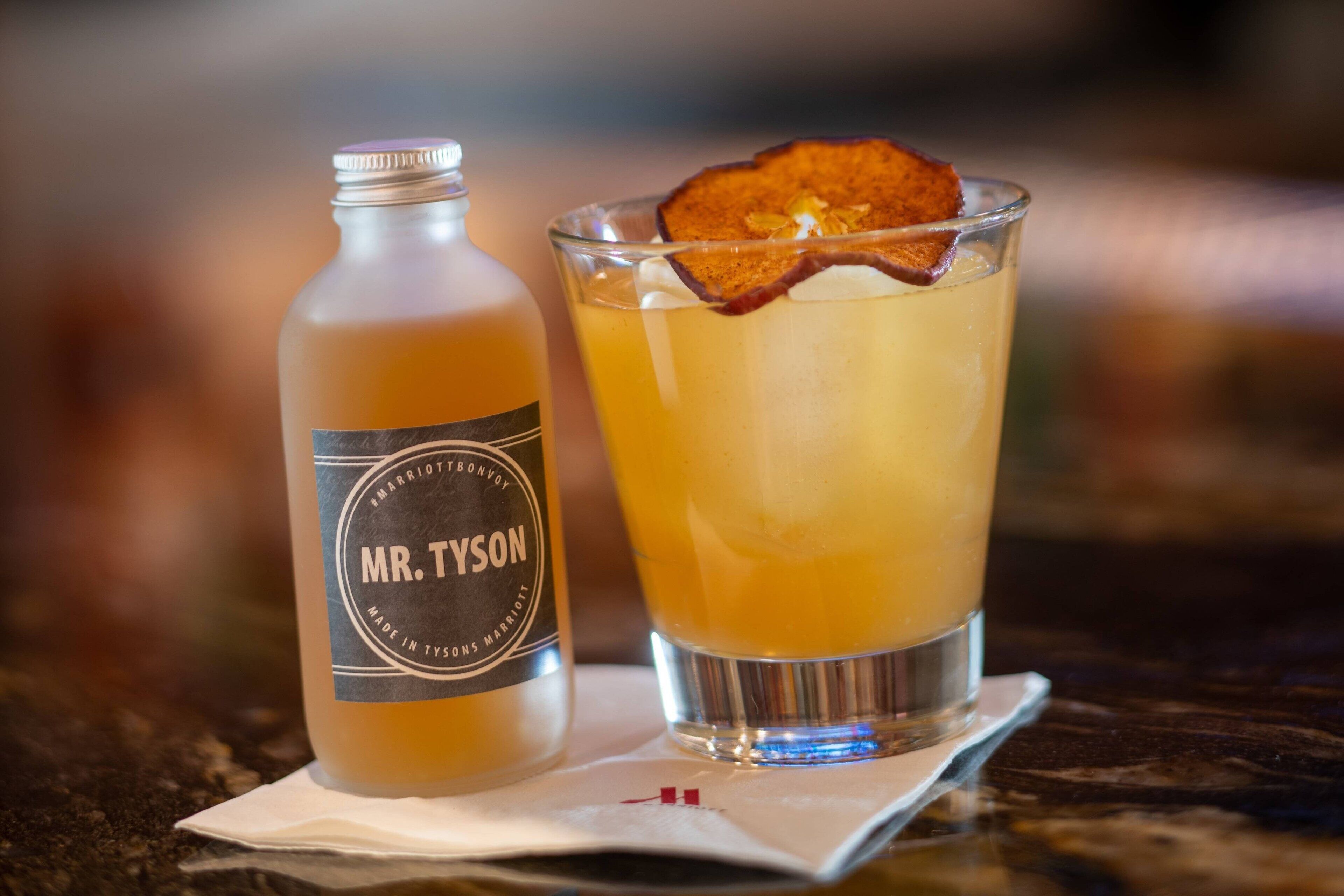 A bottle labeled "Mr. Tyson" and a glass with a garnish on a table.