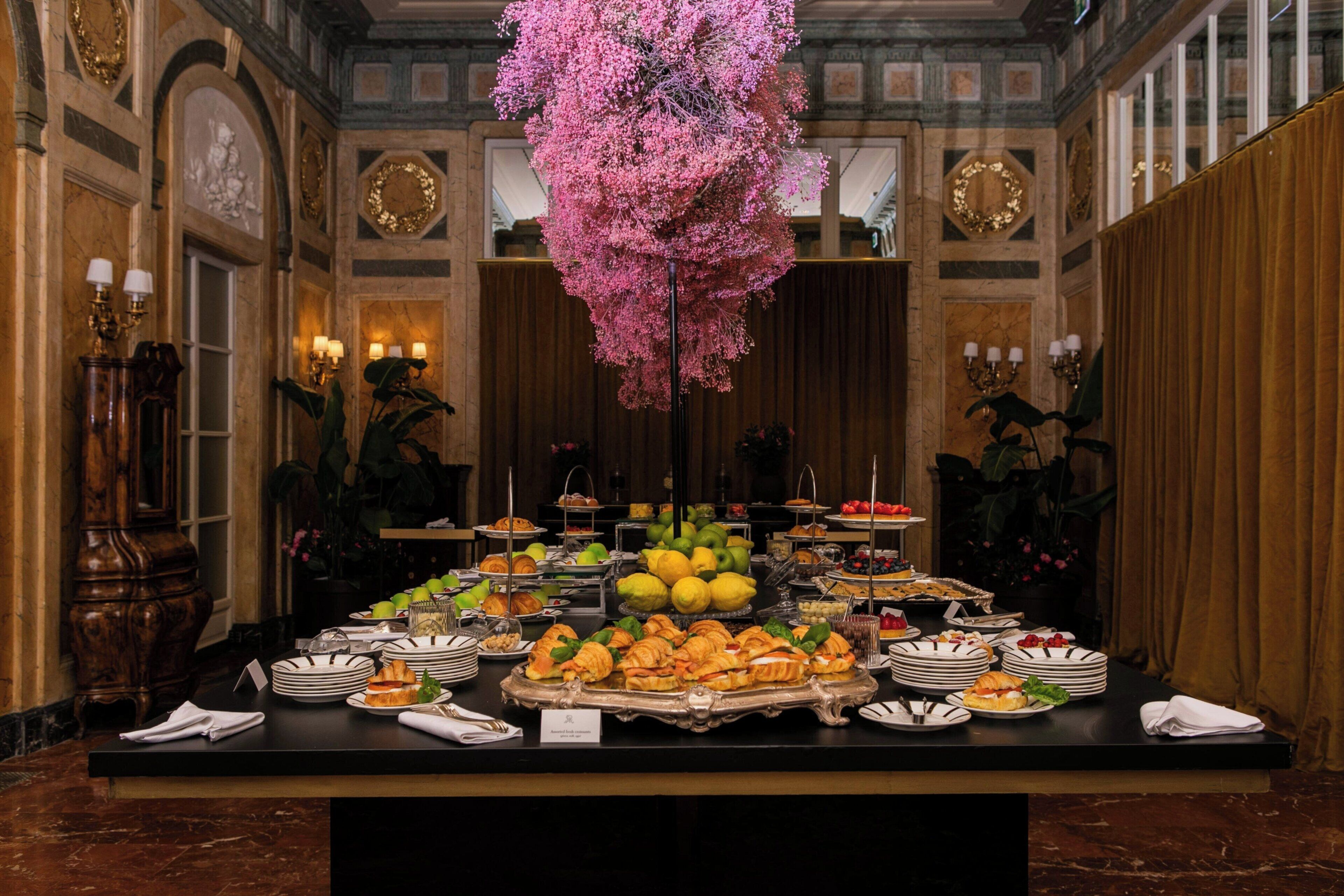 A buffet table with various food items and a decorative pink floral arrangement.
