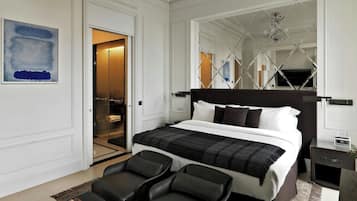 Una camera d'albergo moderna con un letto grande, due poltrone, un tavolino e uno specchio.