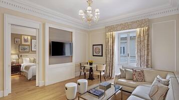 A spacious living room with a flat-screen TV, a sofa, a coffee table, and a dining area with chairs.