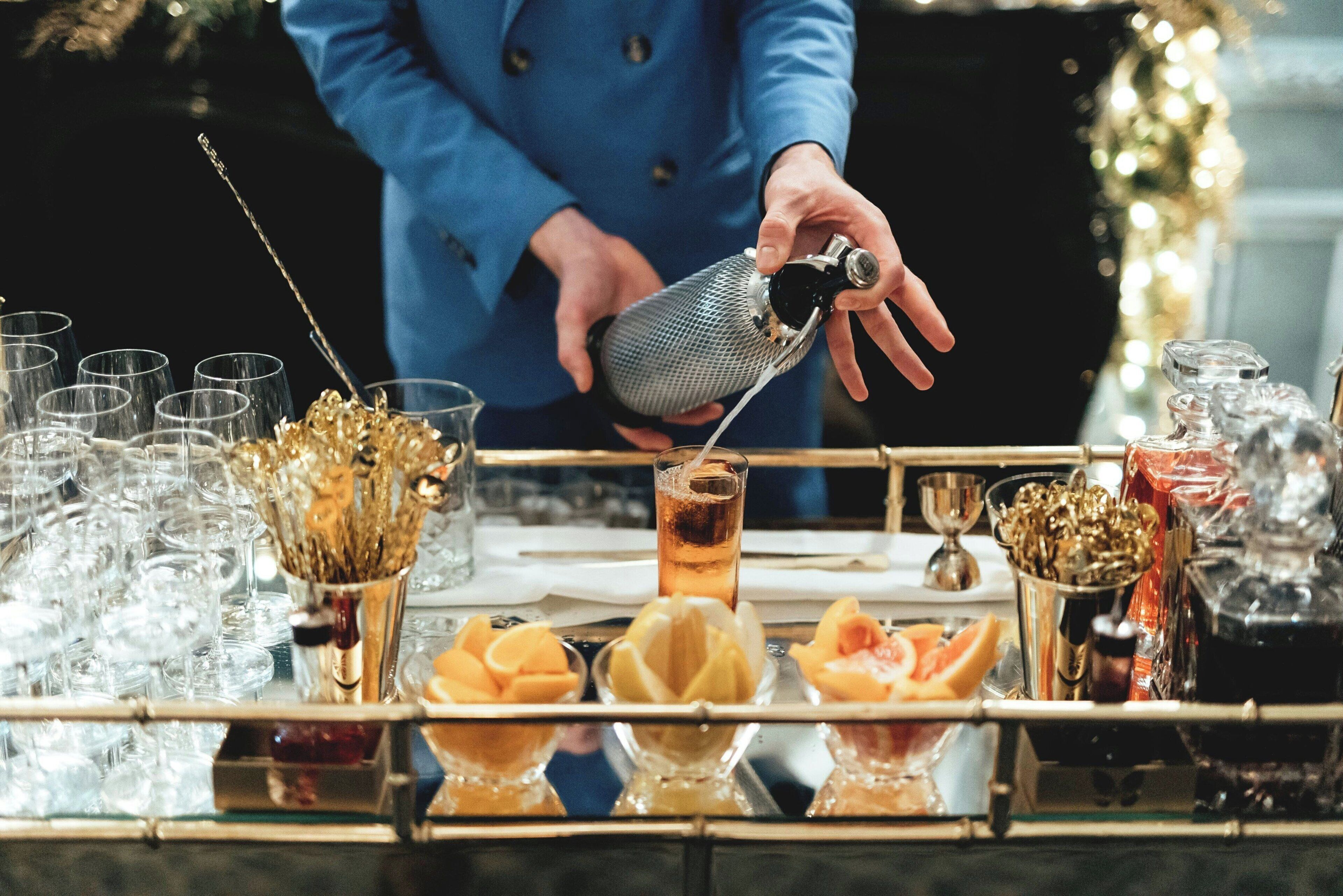 A bar setting with a bartender pouring a drink into a glass.