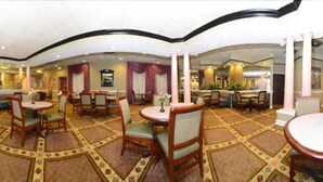A spacious hotel lobby with multiple dining areas, including round tables and chairs, and a central seating area with sofas and a coffee table. - Americas Best Value Inn Baltimore (Baltimore)