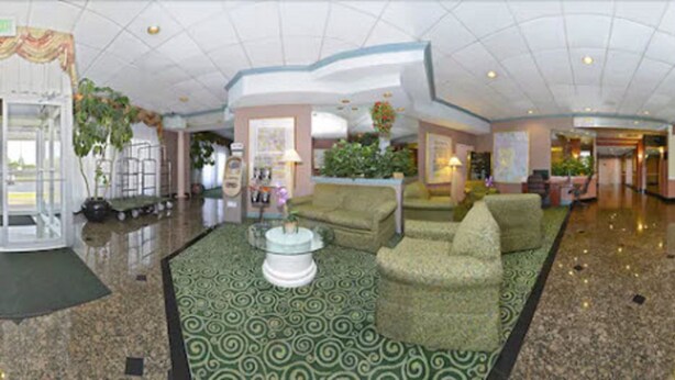 A spacious lobby with a patterned carpet, several sofas, a coffee table, and potted plants. - Americas Best Value Inn Baltimore (Baltimore)
