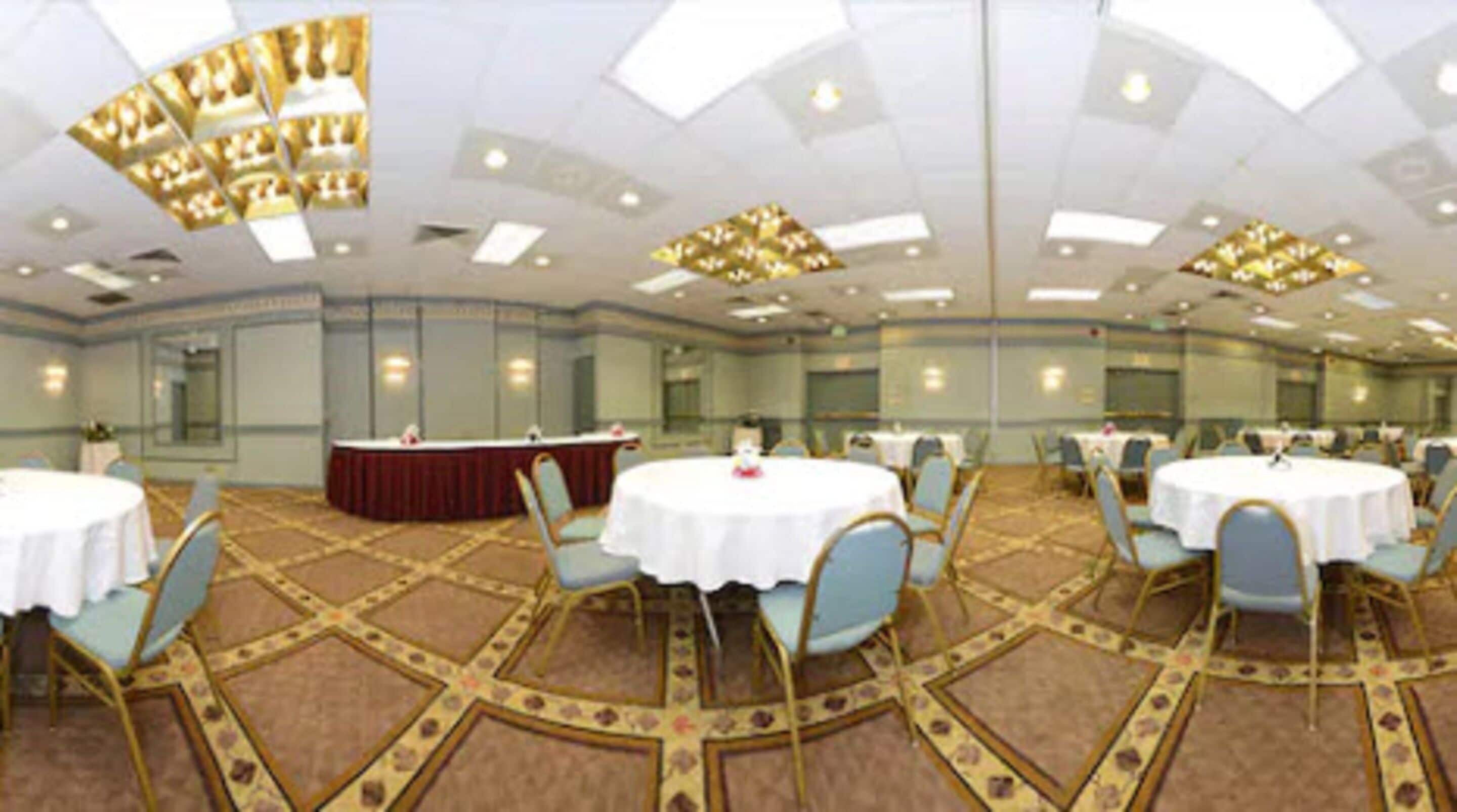 A conference room with round tables, chairs, and a podium.