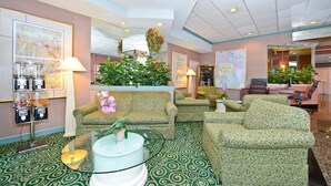 A lobby with patterned carpet, green patterned sofas, a coffee table, and a plant arrangement. - Americas Best Value Inn Baltimore (Baltimore)