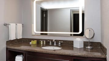 A bathroom with a granite countertop, a sink, a mirror, and a vanity with a towel rack.