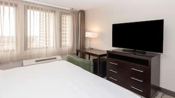 Habitación de hotel con una cama grande, un escritorio, un televisor de pantalla plana, una lámpara y una silla.