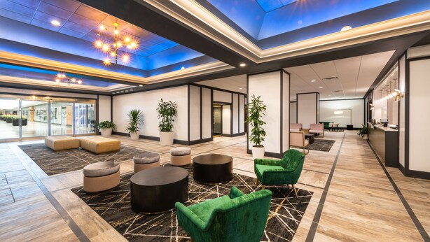 Un hall amplio con techo alto, mobiliario moderno y plantas en macetas.