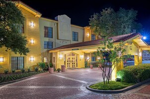 Fachada de hotel de ladrillo, ventanas iluminadas y una entrada acogedora.