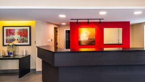 A reception area with a black reception desk, a framed painting, a red accent wall, and a large mirror. - Comfort Inn New Glasgow - Stellarton (New Glasgow)