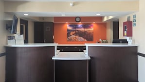 A reception area with two counters, a clock, a large landscape painting, and a Dell computer on the right counter.