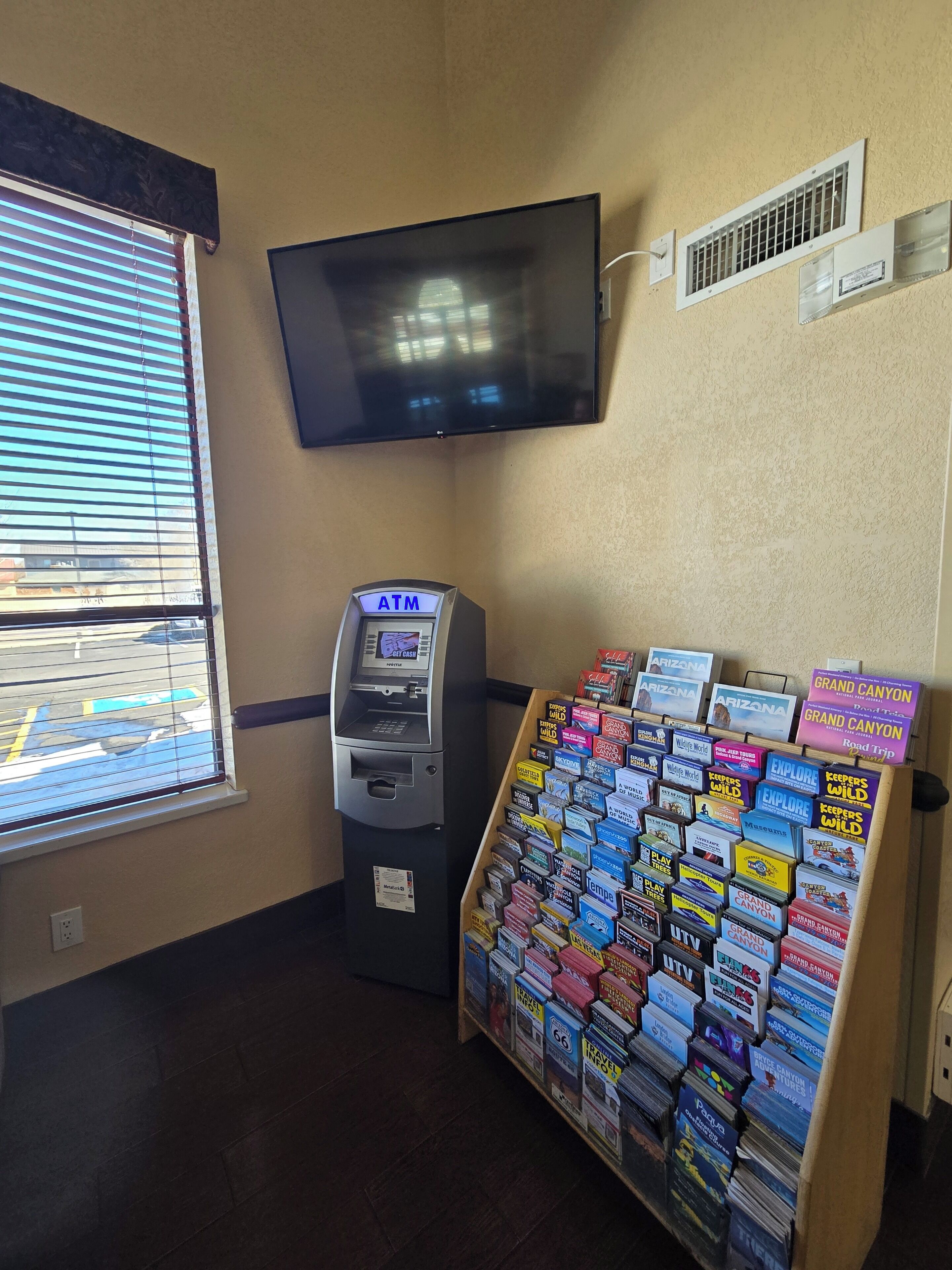 Un cajero automático, un televisor montado en la pared y una exhibición de libros de viajes.