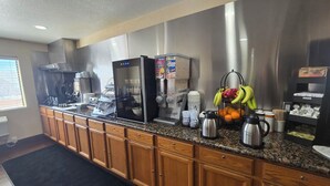 A kitchenette with a refrigerator, coffee maker, and fruit bowl.