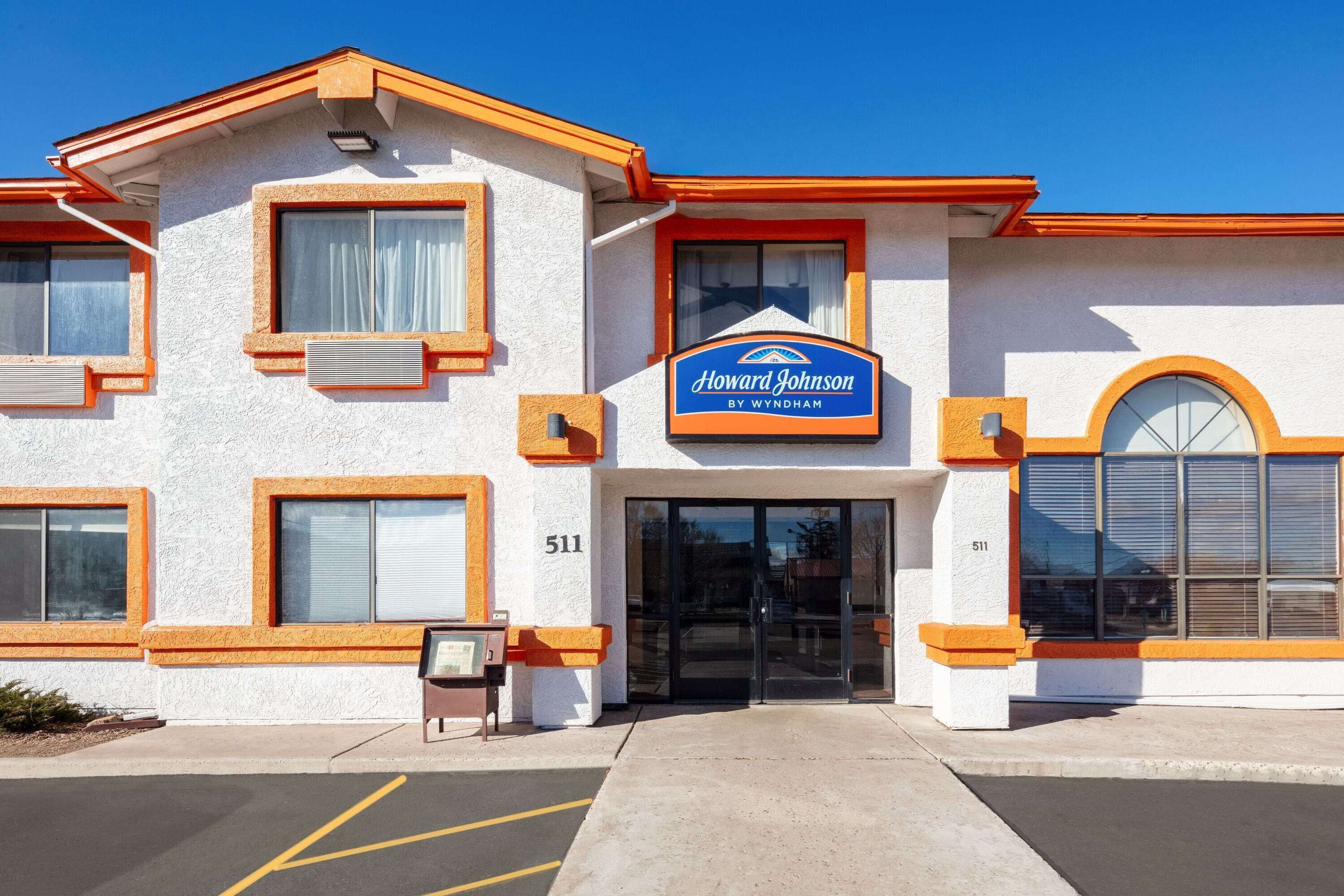 Een hotel met een witte gevel, oranje accenten en een blauw bord waarop staat: "Howard Johnson by Wyndham".