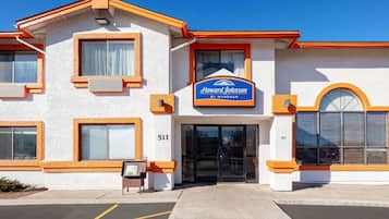 Een hotel met een witte gevel, oranje accenten en een blauw bord waarop staat: "Howard Johnson by Wyndham".