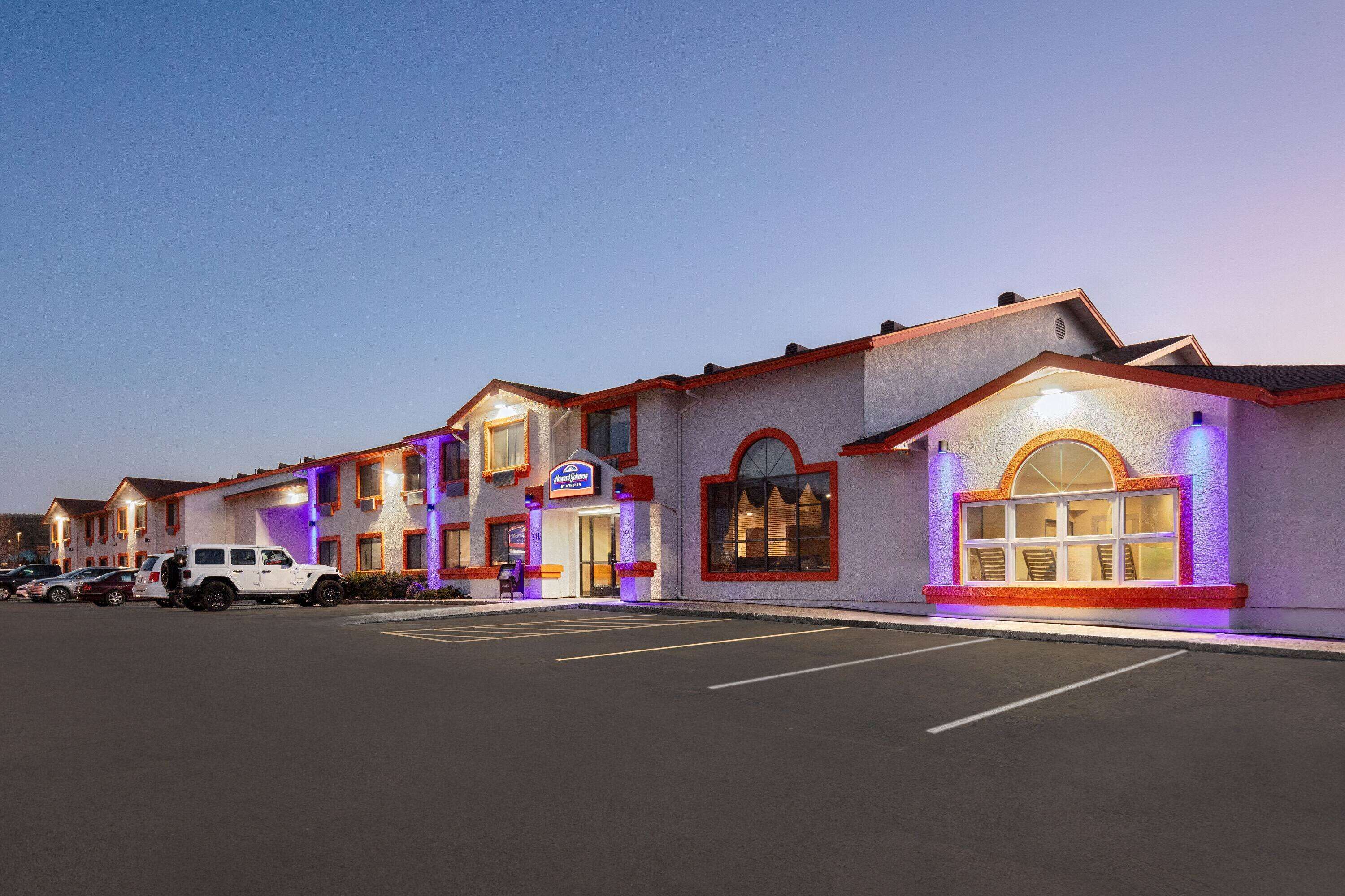A hotel with multiple units, a parking lot, and a clear sky.