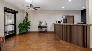 A reception area with a wooden reception desk, a ceiling fan, a clock, and a potted plant. - Quality Inn Dubuque on Hwy 20 (Dubuque)