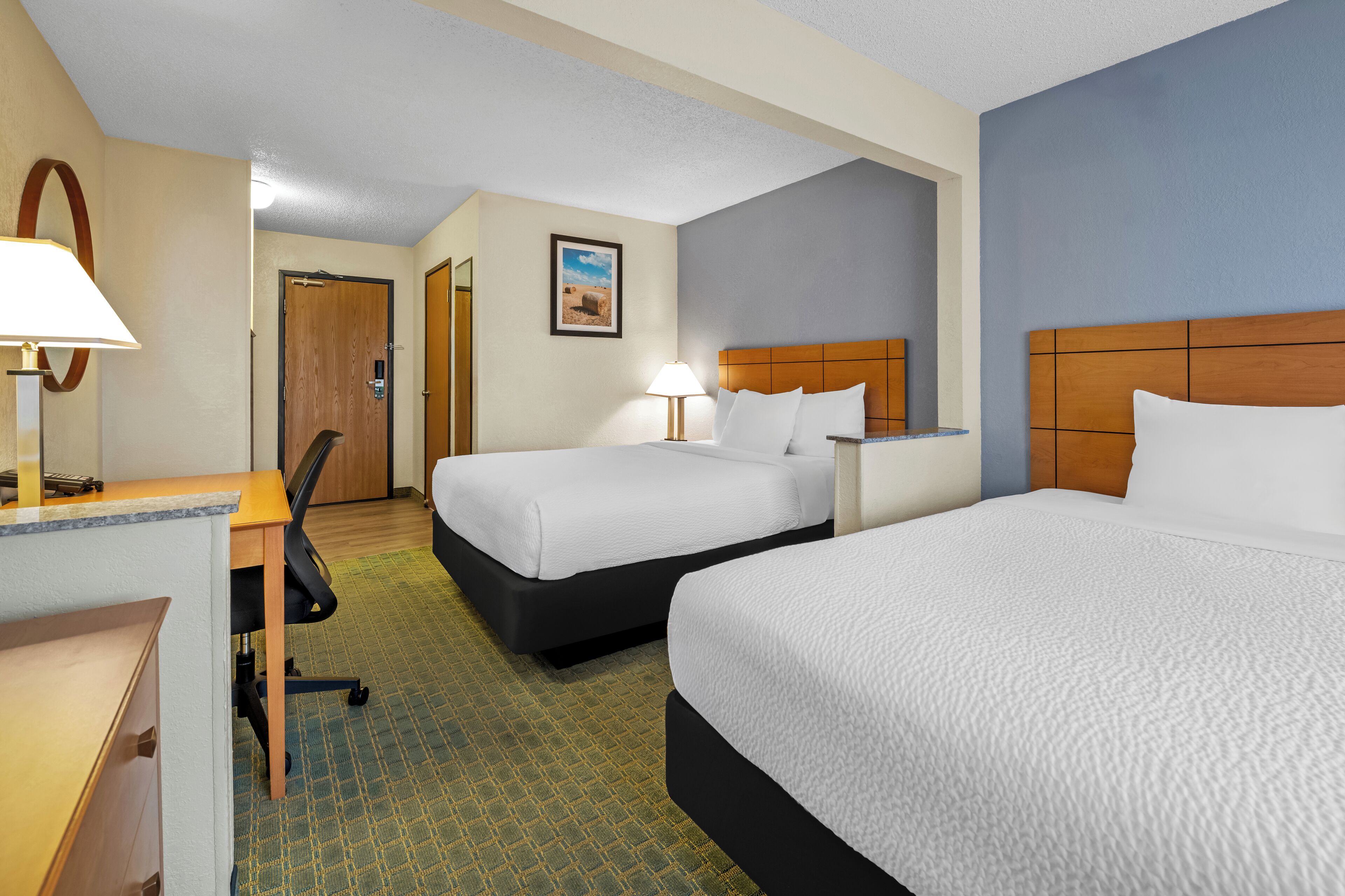 Habitación de hotel con dos camas, un escritorio y una silla.