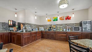 A spacious kitchen with a granite countertop, wooden cabinets, and a stone backsplash. - Quality Inn Dubuque on Hwy 20 (Dubuque)