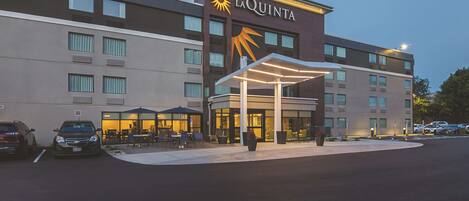 Um hotel com logo de sol, área de estar externa e entrada coberta.