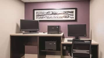 Een moderne kantoorruimte met een bureau, twee monitoren, een toetsenbord, een stoel en een ingelijst beeld aan de muur.