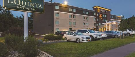 A La Quinta Inn & Suites building with a parking lot, several cars, and a well-maintained lawn area.
