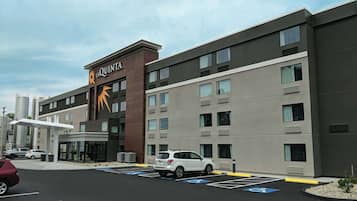 A hotel with a modern design, featuring a prominent sign and a parking lot with handicapped spaces.