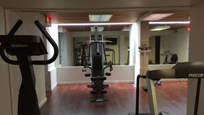 Un gimnasio con una máquina StairMaster elíptica, una cinta de correr Precor y máquinas de pesas.