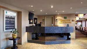 Un área de recepción con mostrador, una planta en maceta y un letrero que dice 'City Inn Suites'.
