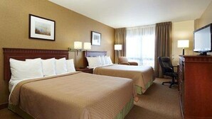 Una habitación de hotel con dos camas, un escritorio, una silla y un televisor.