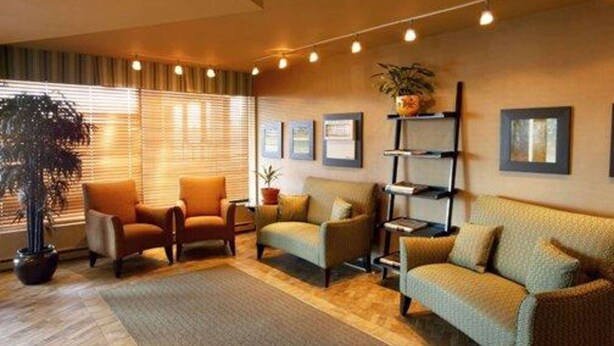 Una sala acogedora con sofá, sillones, una mesa de centro y una estantería.
