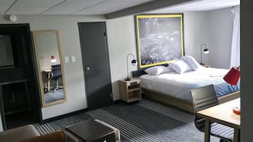 Habitació d'hotel amb llit, escriptori, cadira i un gran mirall.